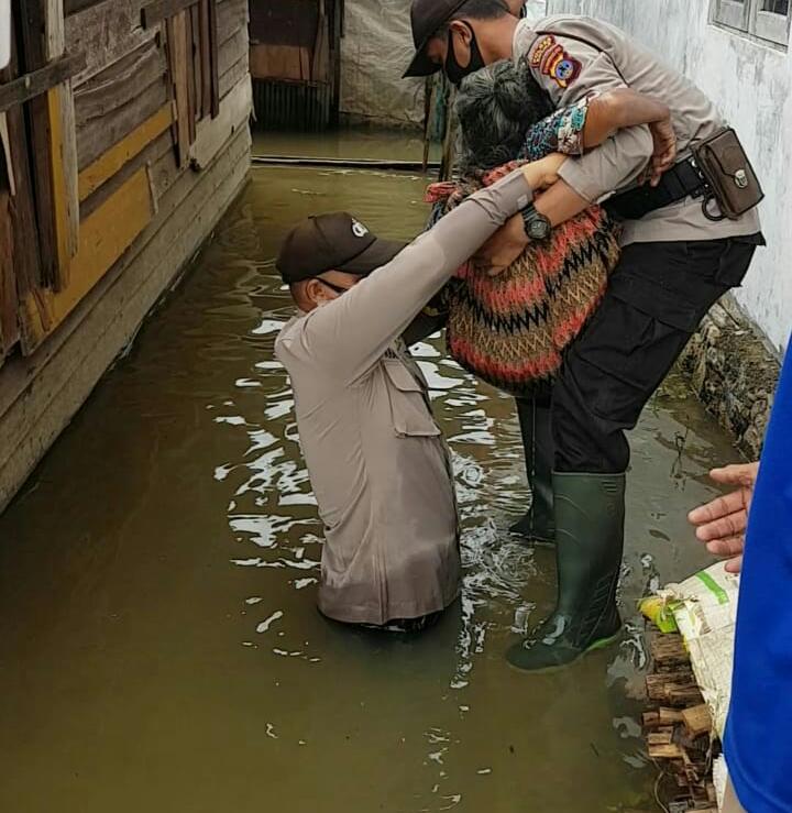 Personil Polisi mengevakuasi seorang nenek akibat rumahnya terendam banjir
